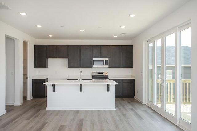 kitchen with a center island with sink, visible vents, light wood-style flooring, recessed lighting, and stainless steel appliances