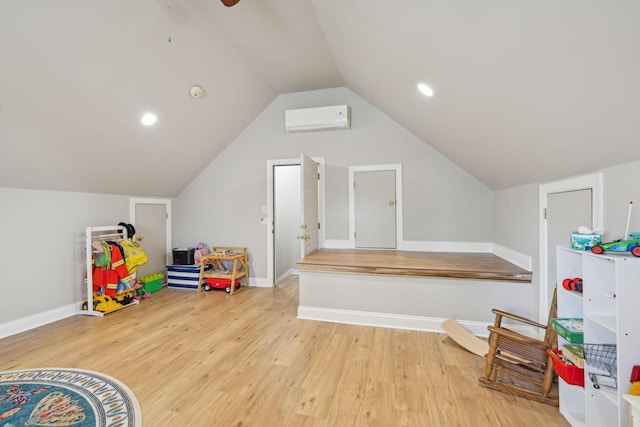 rec room featuring baseboards, lofted ceiling, an AC wall unit, and wood finished floors