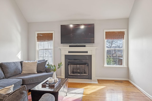 living area with a fireplace with flush hearth, baseboards, and wood-type flooring