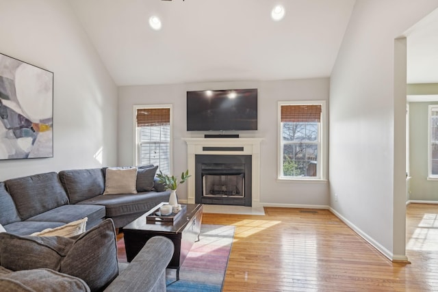 living room with a healthy amount of sunlight, lofted ceiling, and hardwood / wood-style floors