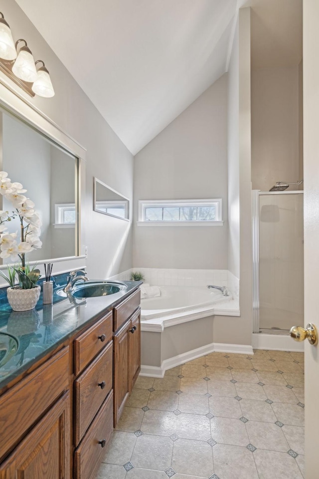 full bath featuring vanity, lofted ceiling, a garden tub, and a wealth of natural light