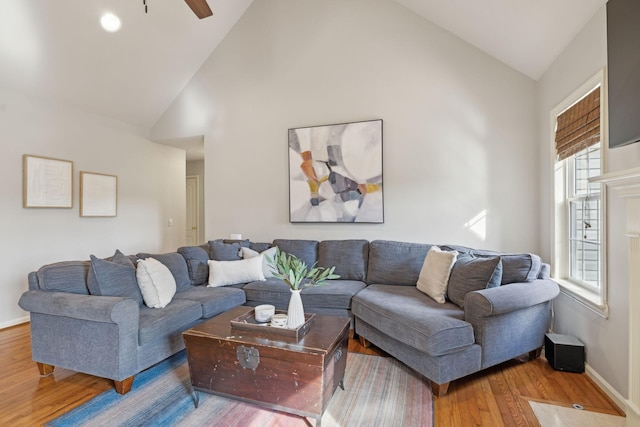 living room with a ceiling fan, wood finished floors, baseboards, and high vaulted ceiling