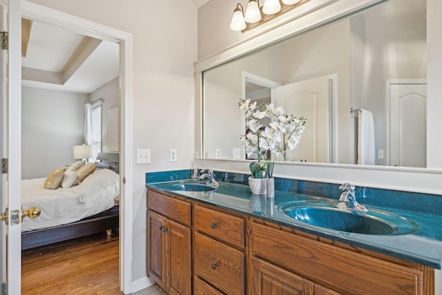 full bath with a sink, connected bathroom, wood finished floors, and double vanity