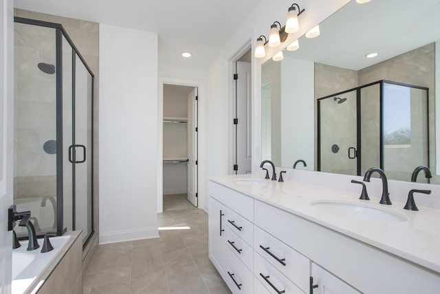 full bath featuring double vanity, a spacious closet, a stall shower, and a sink