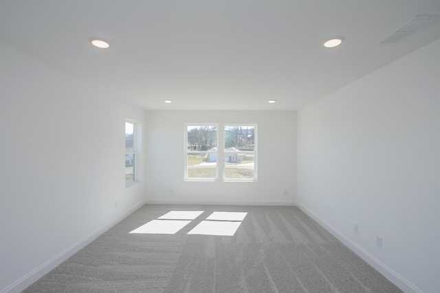 spare room with recessed lighting, visible vents, light carpet, and baseboards