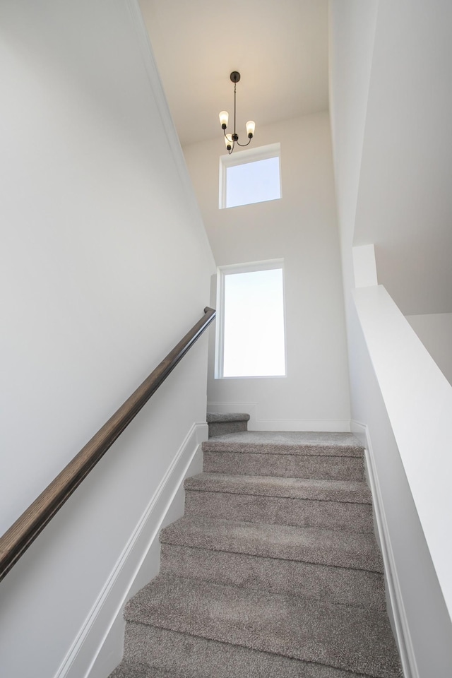 stairs featuring an inviting chandelier, baseboards, and carpet