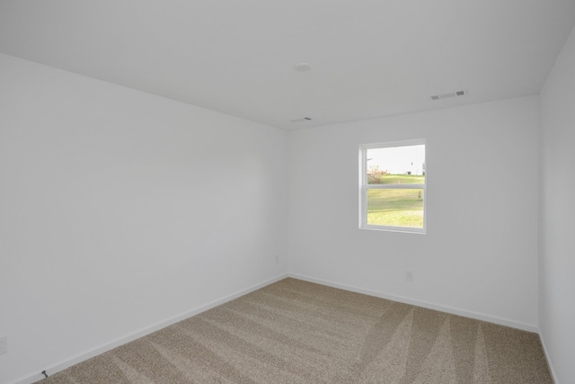 carpeted spare room featuring baseboards and visible vents