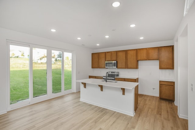 kitchen with a sink, stainless steel appliances, brown cabinets, and light countertops