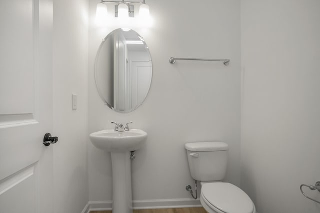 half bath with baseboards and toilet