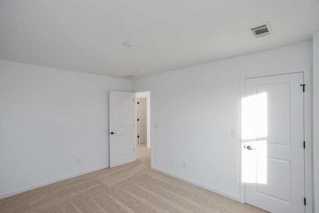 spare room with visible vents, light carpet, and baseboards