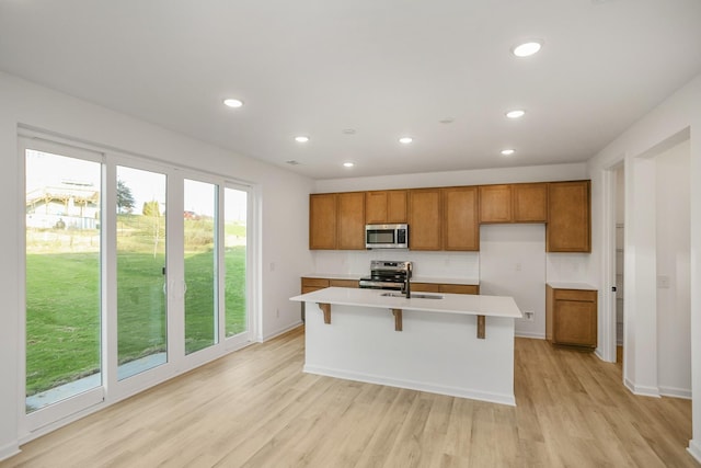 kitchen with brown cabinets, appliances with stainless steel finishes, light wood-type flooring, and light countertops