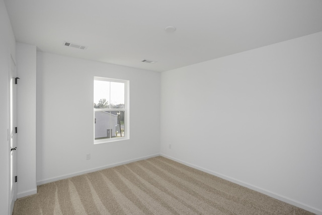 unfurnished room featuring visible vents, light carpet, and baseboards