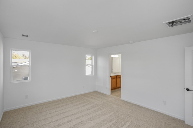 spare room with light colored carpet, visible vents, and baseboards