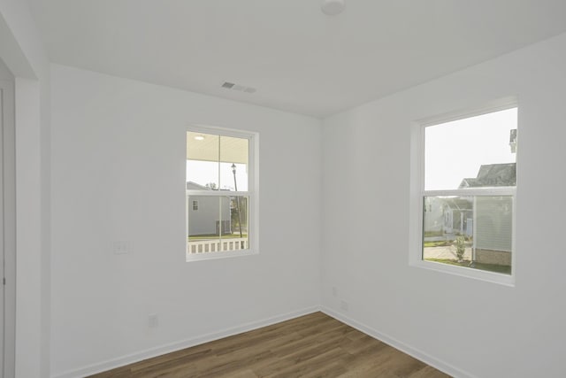 unfurnished room featuring visible vents, wood finished floors, and baseboards