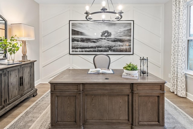 home office with a decorative wall, baseboards, light wood-type flooring, and a chandelier