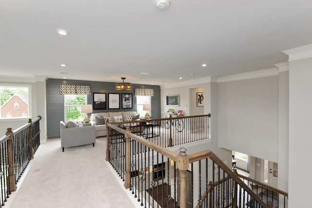 hall featuring an upstairs landing, light colored carpet, an inviting chandelier, and ornamental molding