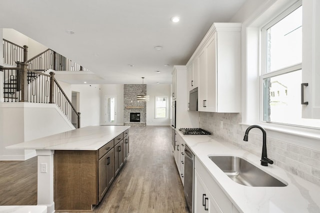 kitchen featuring light wood-style flooring, a sink, open floor plan, a center island, and appliances with stainless steel finishes