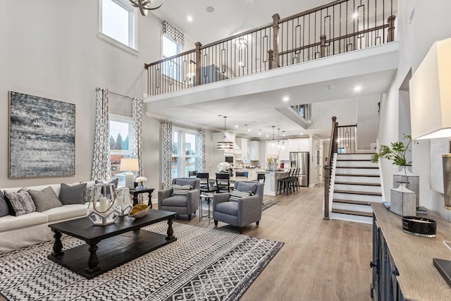 living room with stairs, a high ceiling, recessed lighting, and light wood finished floors