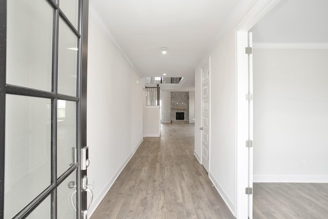 hall featuring baseboards, light wood-style floors, and ornamental molding