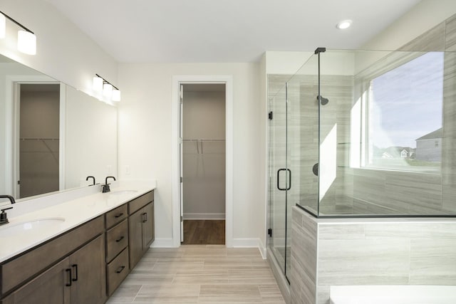 bathroom featuring a sink, baseboards, a stall shower, and double vanity