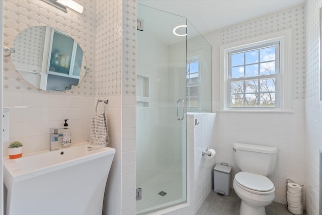 bathroom featuring tile walls, toilet, a stall shower, and wainscoting