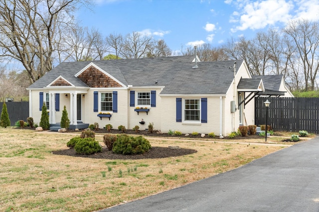 view of front of home with brick siding, a front lawn, and fence