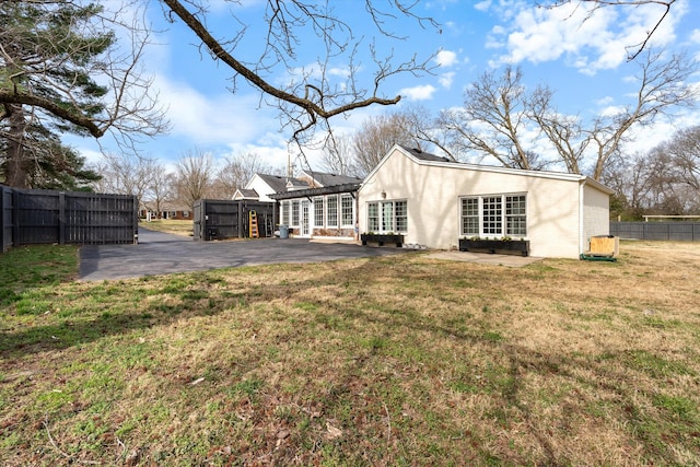 back of property featuring a patio area, a lawn, and fence