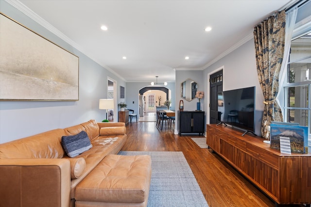 living room with recessed lighting, wood finished floors, arched walkways, and ornamental molding