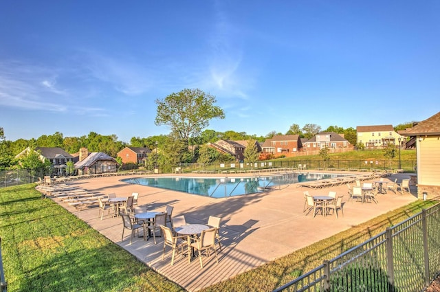 community pool with a patio area, a yard, and fence