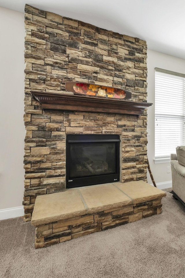 room details featuring a stone fireplace, baseboards, and carpet floors