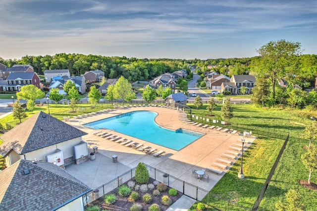 community pool featuring a patio, a yard, fence, and a residential view