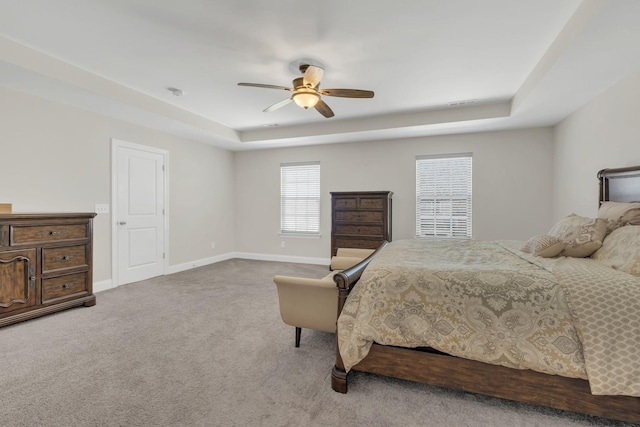 carpeted bedroom featuring visible vents, a ceiling fan, a raised ceiling, and baseboards