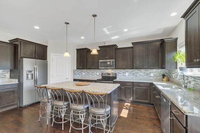 kitchen with dark wood-type flooring, a sink, a center island, dark brown cabinetry, and appliances with stainless steel finishes