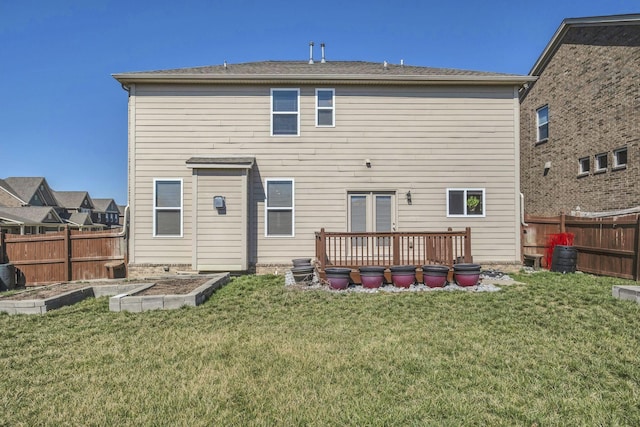 back of house featuring a garden, a lawn, a deck, and fence