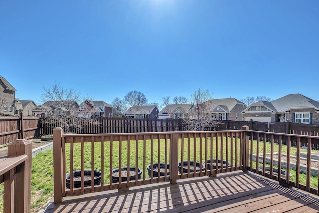 wooden deck featuring a yard, a residential view, and a fenced backyard