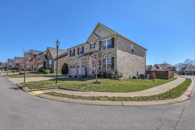 traditional-style house featuring a front lawn, fence, a residential view, concrete driveway, and an attached garage