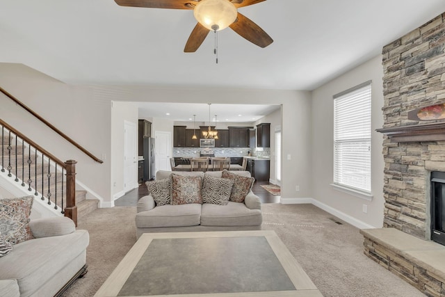 carpeted living room with a stone fireplace, stairs, visible vents, and baseboards