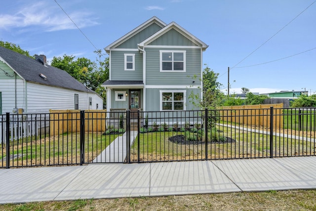 view of front of house with a fenced front yard, board and batten siding, a front lawn, and a gate