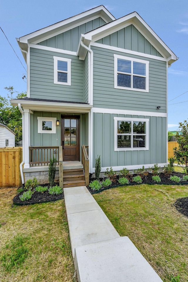 view of front of home with a porch, board and batten siding, a front yard, and fence