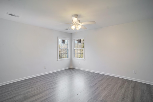 empty room featuring visible vents, baseboards, ceiling fan, and dark wood-style flooring