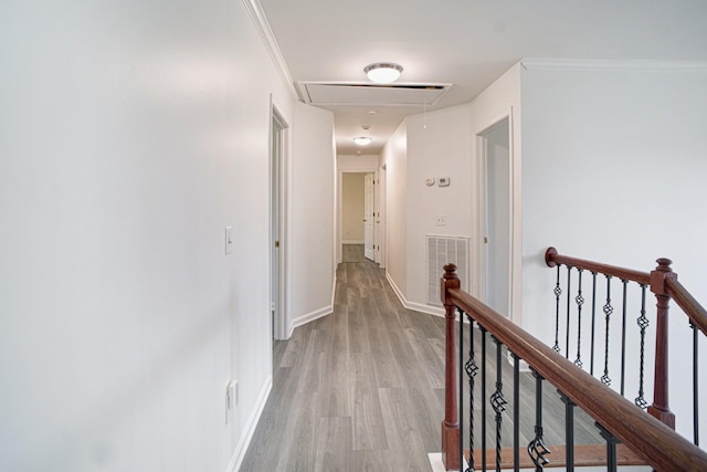 hall with visible vents, baseboards, attic access, light wood-type flooring, and an upstairs landing