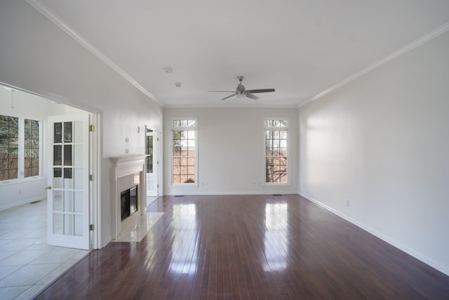 unfurnished living room featuring a high end fireplace, baseboards, ornamental molding, hardwood / wood-style flooring, and a ceiling fan