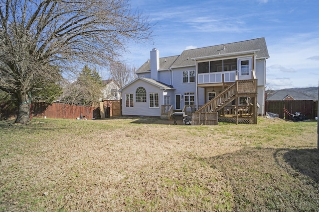 rear view of property with fence, a wooden deck, a yard, a sunroom, and a chimney