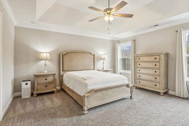 carpeted bedroom with visible vents, baseboards, a tray ceiling, and ornamental molding