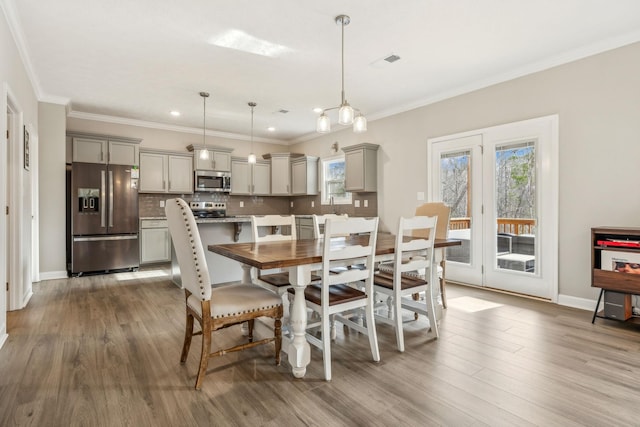 dining room featuring crown molding, wood finished floors, visible vents, and baseboards