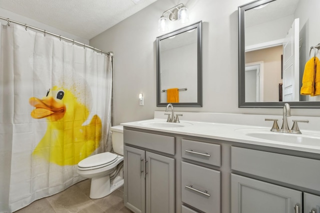 bathroom featuring a textured ceiling, double vanity, toilet, and a sink