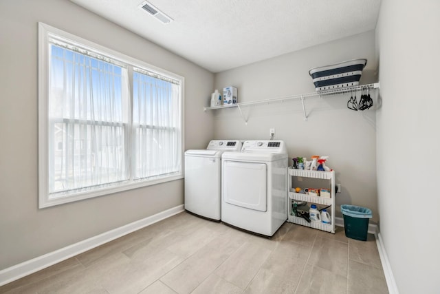 laundry area with baseboards, visible vents, washing machine and clothes dryer, laundry area, and a textured ceiling