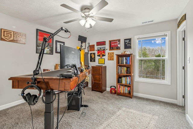 home office featuring visible vents, baseboards, carpet floors, a textured ceiling, and a ceiling fan