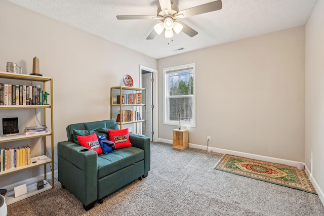 living area with visible vents, baseboards, carpet floors, ceiling fan, and a textured ceiling