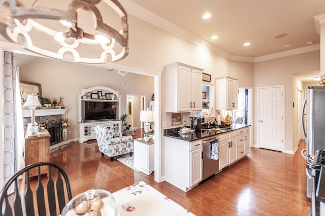 kitchen featuring dark countertops, crown molding, an inviting chandelier, wood finished floors, and stainless steel appliances